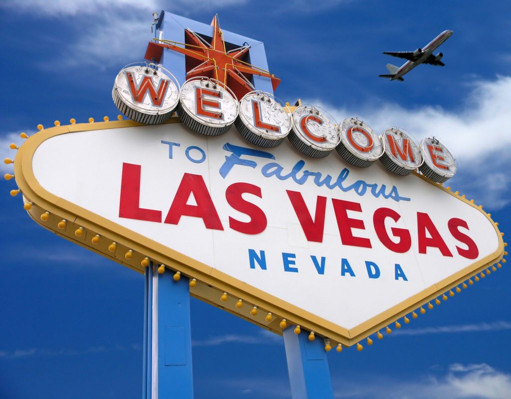welcome to las vegas sign with plane flying overhead 