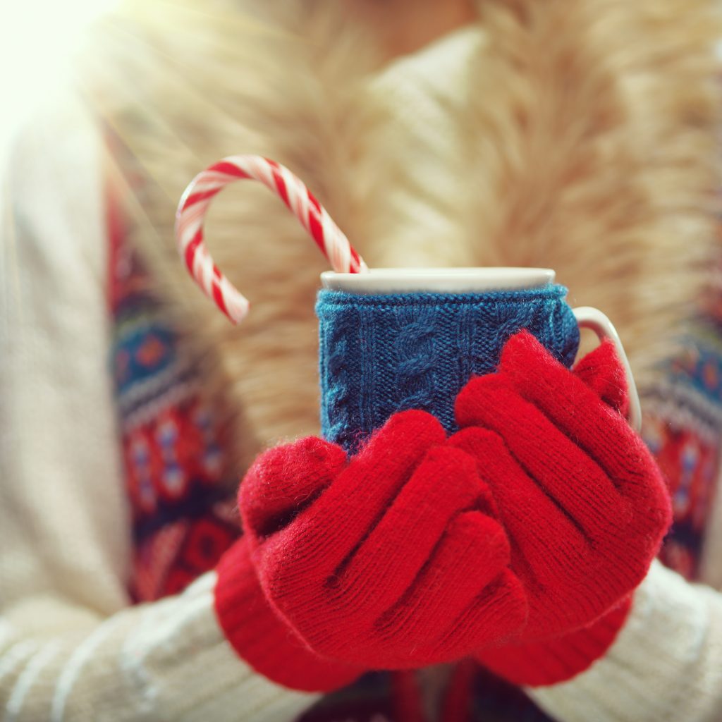 Woman with mittens holding mug of hot cocoa