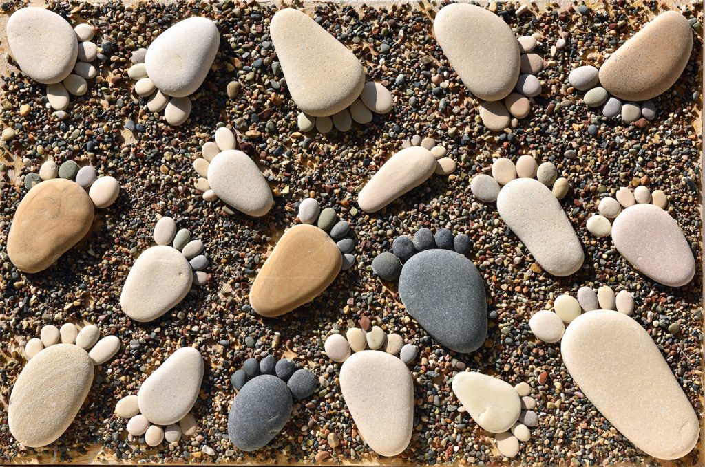 Pebble stones arranged like footprints on the beach