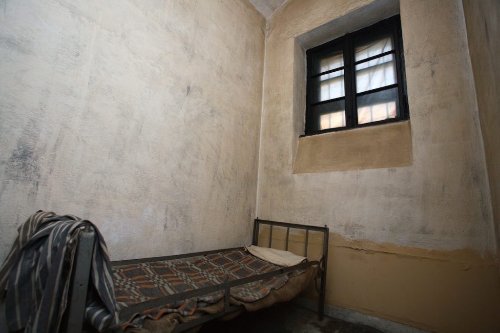 old jail cell with a bed and window in the frame