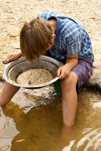 a young boy looks into the pan looking for gold