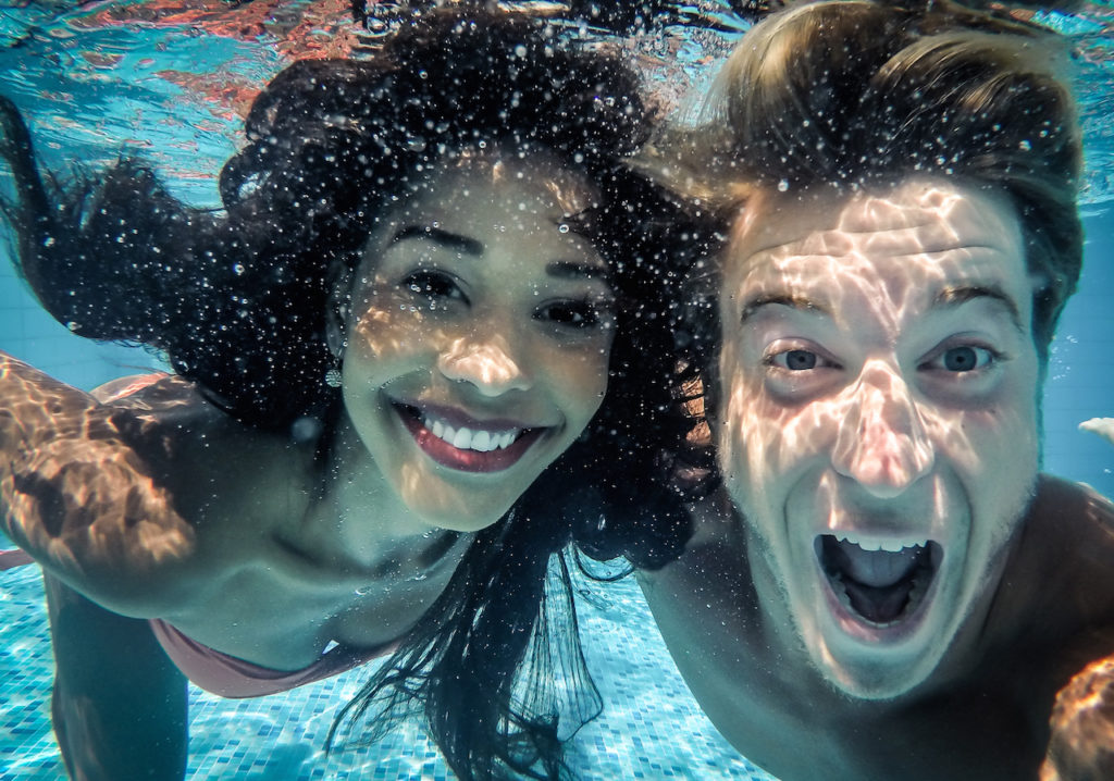 attractive young couple taking a picture and smiling under water