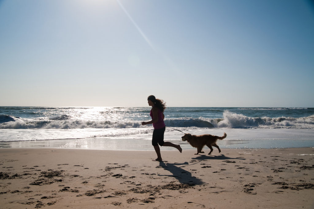 Girl and her dog running on the beach