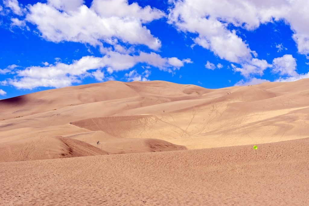 colorado sand dunes with a bright blue cloud filled sky 