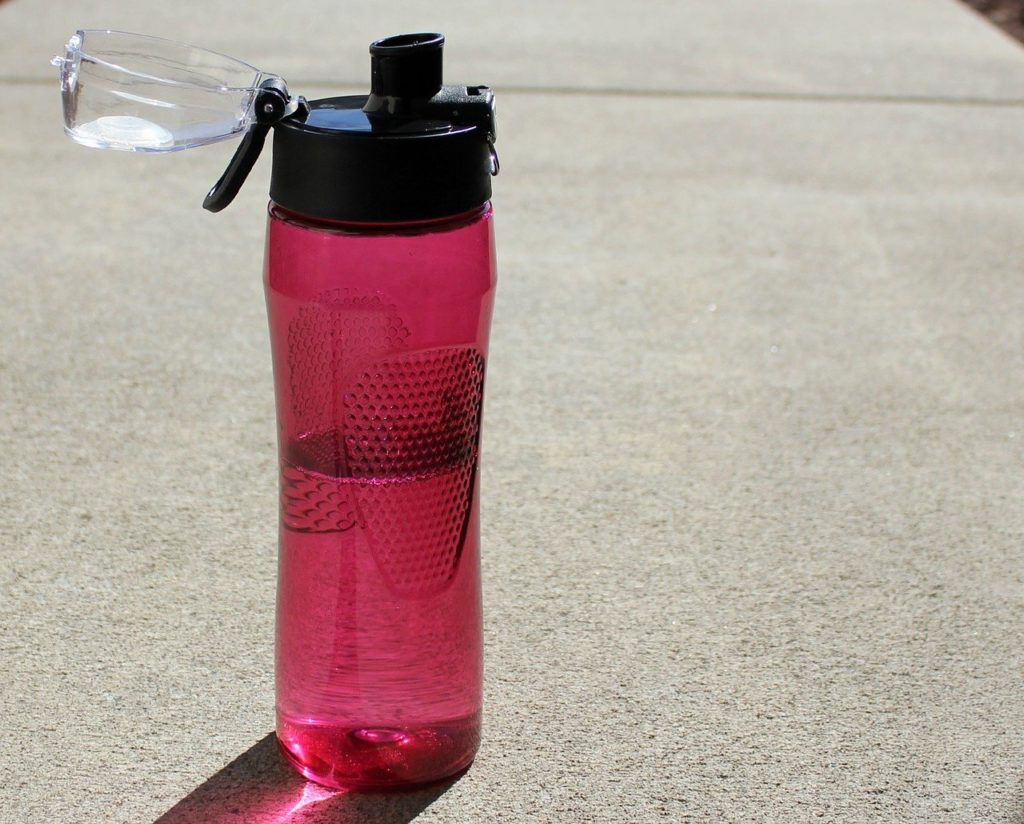 pink reusable water bottle on the sidewalk